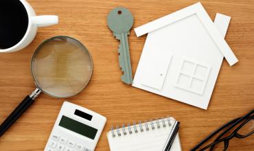 J. Adam Abram Appointed Chair of North Carolina Housing Finance Agency Keys and a calculator on a wooden table