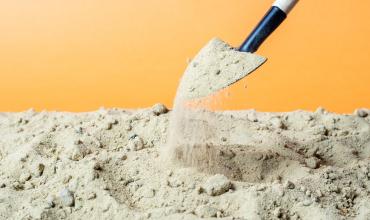 Shovel picking up dirt with a yellow background