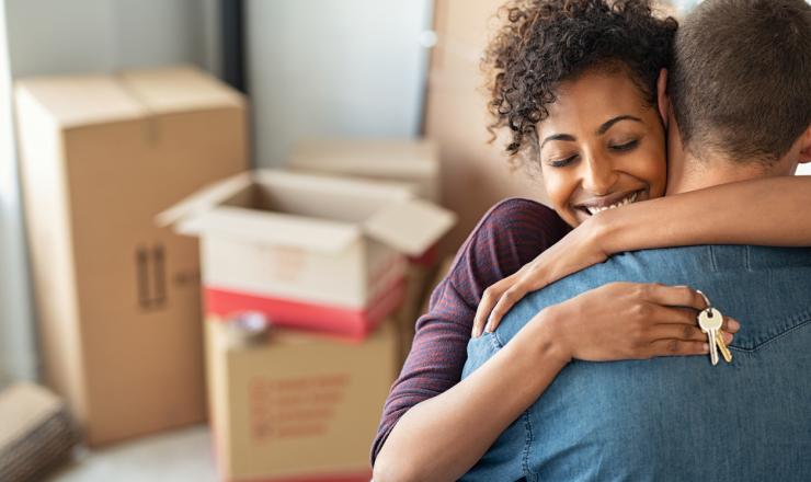 A couple hugging and holding a key to their new home