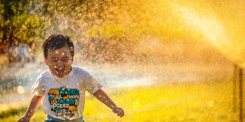 The Hidden Costs of Buying Your First Home A little boy running through the sprinklers on a sunny day